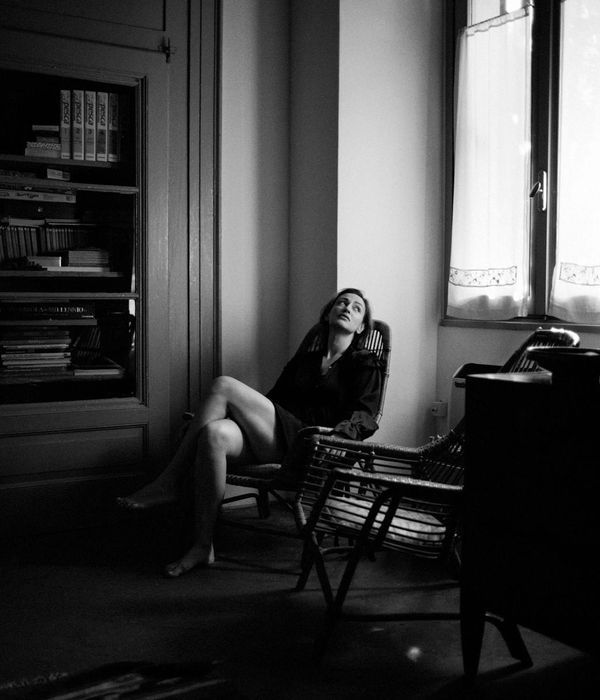 Woman performing a calm, flowing exercise in a minimalist dark room.